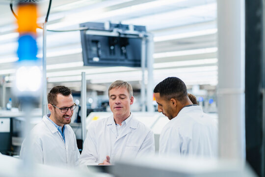 Technicians in lab coats discussing in electronics factory