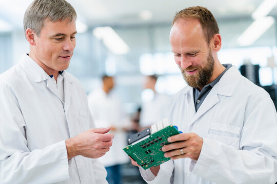 Electrical technicians checking motherboard in electronics factory