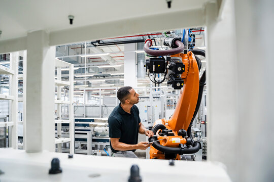 Technician examining industrial robot in a factory