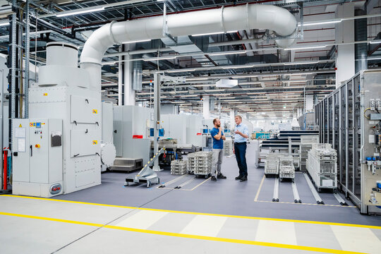 Businessman and employee talking in a factory