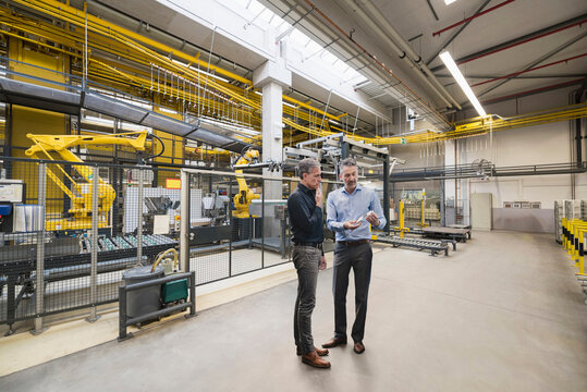 Businessmen planning in front of machinery at factory