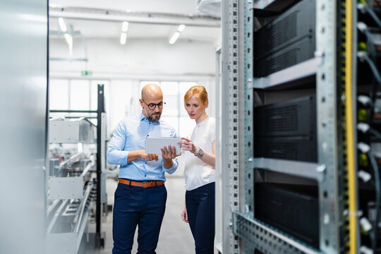 Businessman and businesswoman having discussion over tablet PC in factory