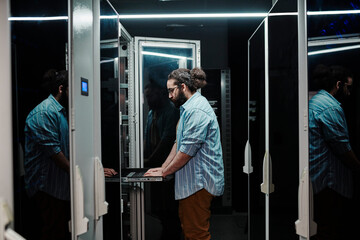 IT expert working by servers standing in control room