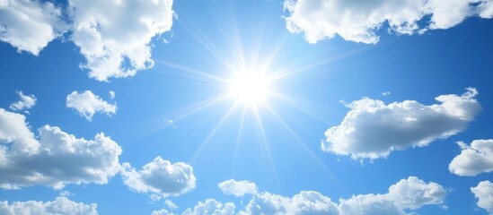 Radiant sunlight pierces through fluffy clouds in a vast expanse of blue sky