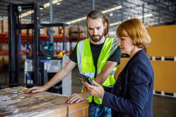 Manager sharing tablet PC with colleague by stocks in warehouse