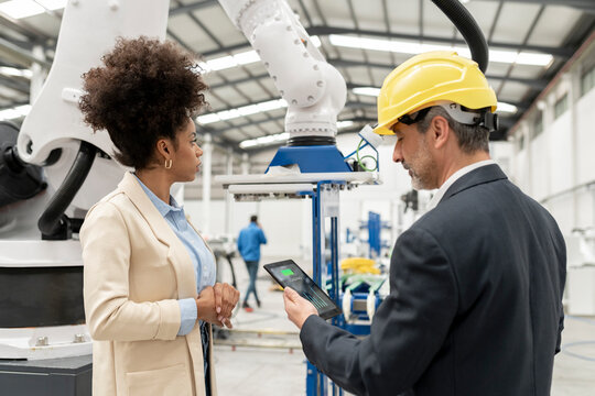 Engineer holding tablet PC standing with developer in factory
