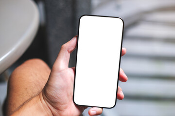 Mockup image of a man holding mobile phone with blank white screen in cafe