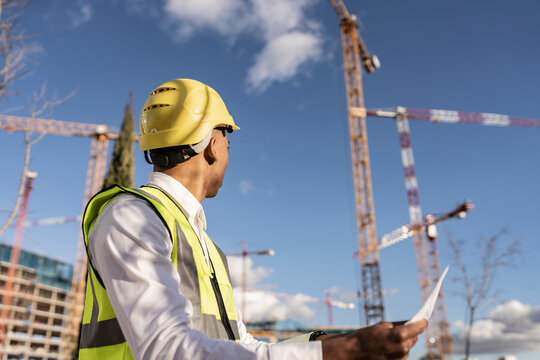 Architect wearing hardhat working at construction site on sunny day