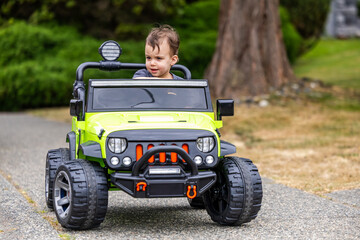 Fototapeta premium Young Toddler Driving Electric Toy Car Outdoors in Vancouver, BC