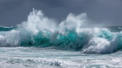 Fototapeta premium Turbulent waves rise and crash onto the sandy beach, creating white foam and splashes under a dark, cloudy sky in the late afternoon.