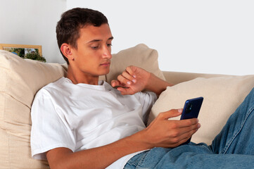 young man with mobile phone lying on sofa at home