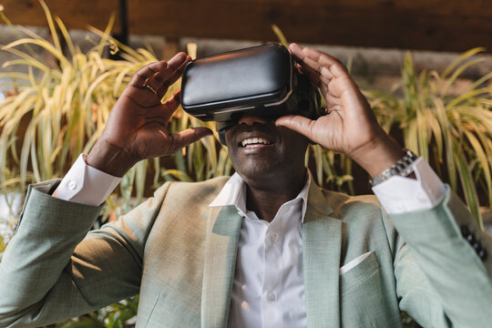 Happy businessman with virtual reality simulator at cafe - Powered by Adobe