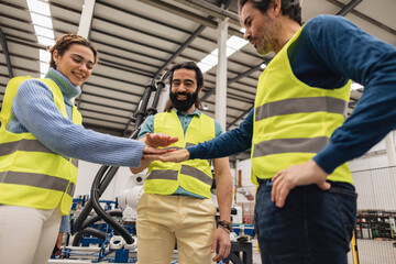 Happy engineers stacking hands in factory