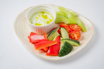A vibrant selection of sliced vegetables served with a creamy dip, perfect for snacking