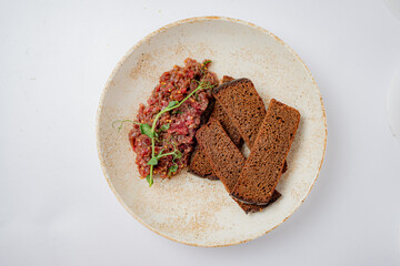A tasty dish of chopped meat with herbs served with slices of dark bread