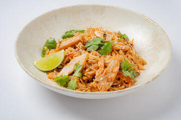A vibrant bowl filled with spicy rice, tender chicken slices, fresh cilantro, and a lime wedge