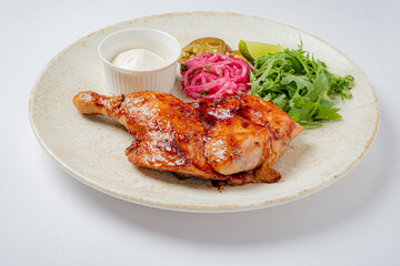 Succulent grilled chicken on a plate surrounded by vibrant greens, tangy pickles, and a rich sauce