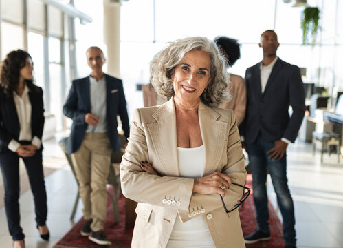 Confident senior businesswoman with arms crossed standing at office