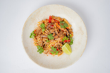 A vibrant plate of stir-fried noodles topped with herbs, lime, and spices delights the senses