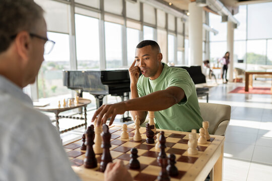 Businessman picking up chess piece playing board game with colleague in office