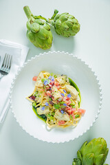 A vibrant bowl of pasta with artichokes and herbs highlights modern culinary artistry