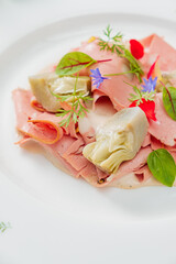 Luxurious cold cuts are artfully garnished with vibrant flowers and fresh herbs