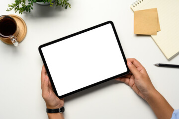 Obraz premium Hands holding a digital tablet with a blank white screen on a clean desk