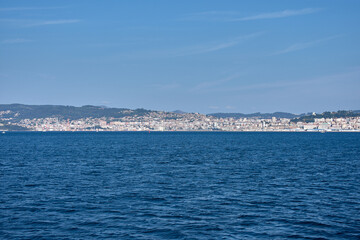 Coastal cityscape of Vigo captured from the center of the Vigo Estuary with a skyline of buildings and a clear sky
