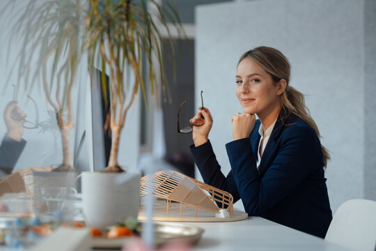 Smiling businesswoman with wooden leaf shape model at desk