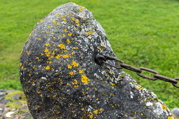 Close-Up of Weathered Stone with Metal Chain in a Green Field
