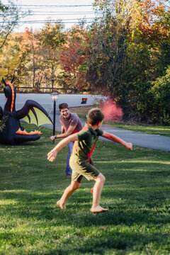 Man and child play with color powder near inflatable dragon outside