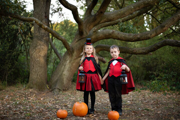 Children dressing for Halloween with pumpkins and lanterns.