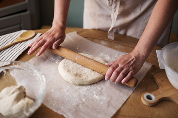 Woman rolling dough on the kitchen table, home baking