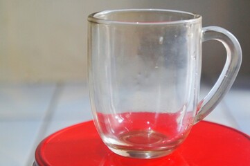 Empty glass cup for espresso coffee isolated on red container.Without people.