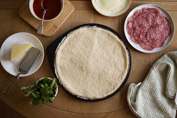 Cooking pizza at home, dough and ingredients on the table