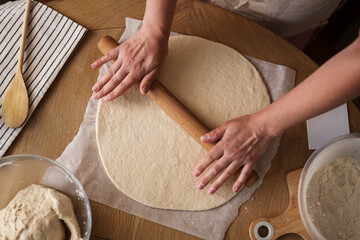 Female hands rolling dough, home baking