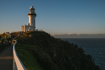 Lighthouse on cliffside at Byron Bay during golden sunset.
