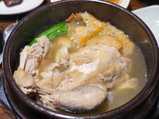 Traditional Korean ginseng chicken soup (Samgyetang) with crispy scorched rice (Nurungji) served in a hot stone pot.