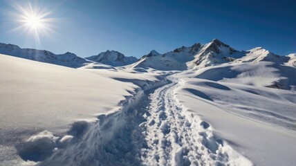 Sunlit snowy mountain path with clear blue sky and distant peaks.