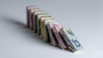 Dominoes made of currency notes arranged in row, symbolizing financial risk and economic instability