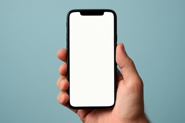 Close-up of a hand holding a modern smartphone with a blank white screen against a soft blue background.