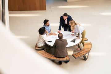 Multiracial business colleagues discussing at table in corridor