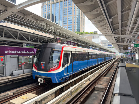 Bangkok, Thailand - June 22, 2025: Front view of BTS skytrain arriving at elevated station under urban skyline