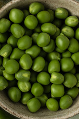 Close-up of green peas in beige ceramic bowl, top view. Macro food photography
