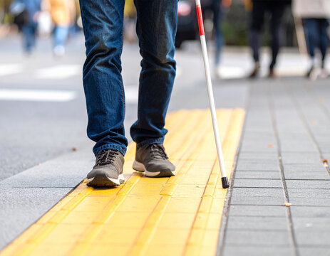 A blind person walks on the sidewalk guiding block