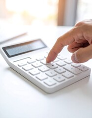 Close-up of a hand using a calculator on a white surface
