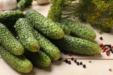 Making pickles. Fresh cucumbers, peppercorns and dill on light wooden table, closeup