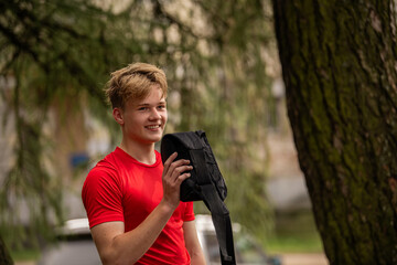 Young man in red shirt drinking from water bottle in black hip pack
