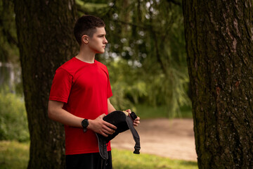 Young man in red shirt drinking from water bottle in black hip pack