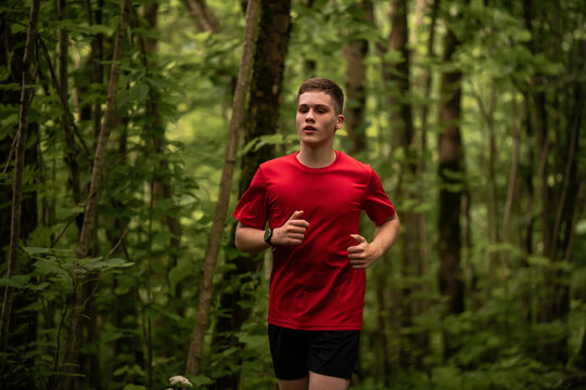 young boy running cross country in summer forest
